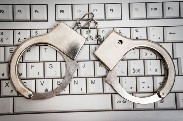 Вид сверху клавиатуры и наручников - концепция киберпреступности
 - Фото, изображение