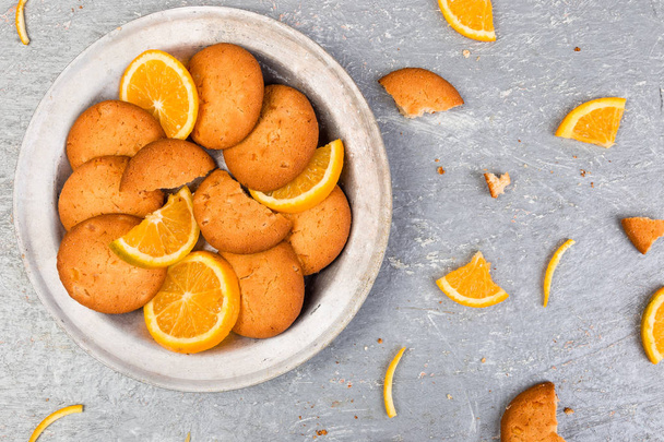 Biscoitos e frutas cítricas laranja em placa de metal em fundo cinza. Depósito plano
 - Foto, Imagem
