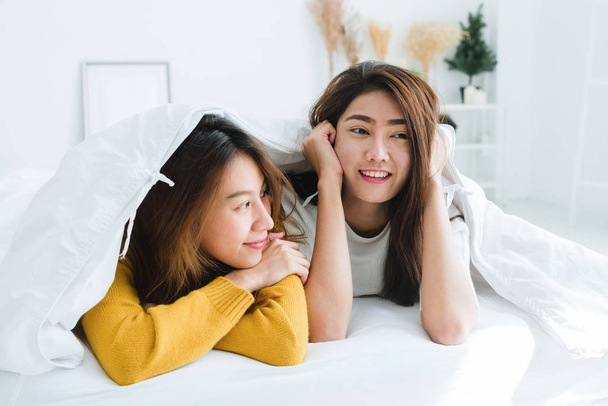 Вид зверху лесбіянок щасливі пари красиві молоді азіатські жінки показані сюрприз і дивлячись на камеру, лежачи в ліжку під ковдрою. Смішні жінок після пробудження. Лесбіянки пари разом в приміщенні концепції - Фото, зображення