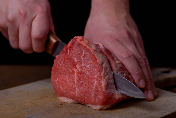 Руки чоловік ріже м'ясо яловичини
 - Фото, зображення