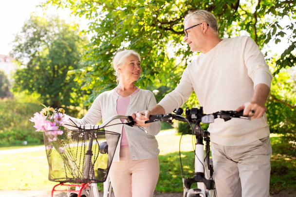 happy senior couple with bicycles at summer park - Photo, Image
