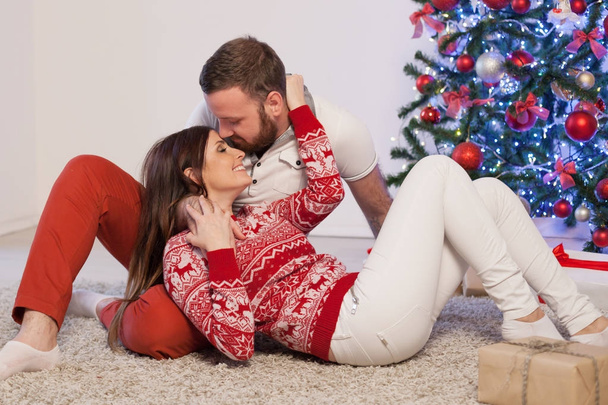 el tipo con la chica tumbada en el suelo en el árbol de Navidad de año nuevo
 - Foto, Imagen
