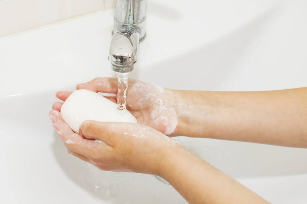 Handen wassen met zeep onder de kraan met water - Foto, afbeelding