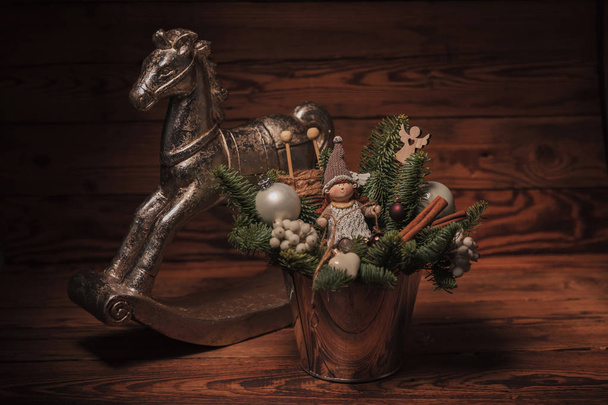 balde com decorações de Natal perto de cavalo de brinquedo
  - Foto, Imagem