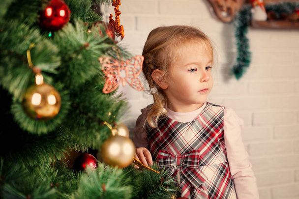 Pretty little child near Christmas tree. - Foto, Imagem