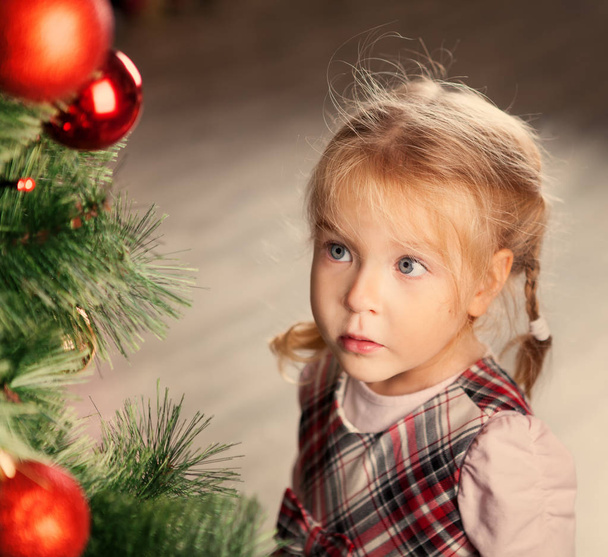 Pretty little child near Christmas tree. - Photo, image