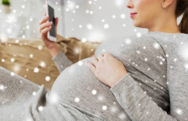 happy pregnant woman with smartphone at home - Фото, изображение