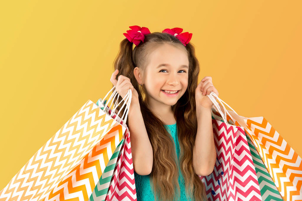 Eladó. Aranyos kislány a sok bevásárló szatyrok. Portréja egy gyerek a vásárlás. - Fotó, kép