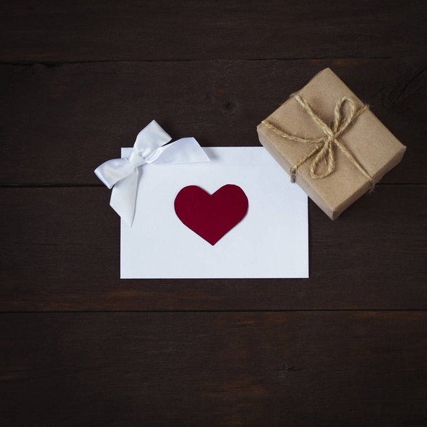 Композиція з конвертом з серцем, бантом і подарунковою коробкою на де
 - Фото, зображення