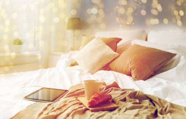 PC tableta, taza de café y croissant en la cama en casa
 - Foto, imagen