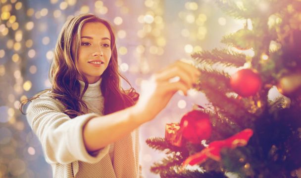 happy young woman decorating christmas tree - Фото, изображение