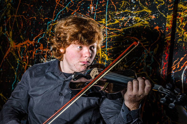 Zrzavý pihovatý chlapec hrající housle s různými pocity o - Fotografie, Obrázek