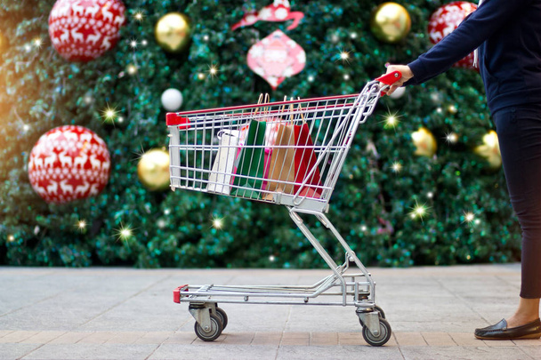 Compras de Navidad - comprador femenino con bolsas de papel en el carrito de compras
 - Foto, Imagen
