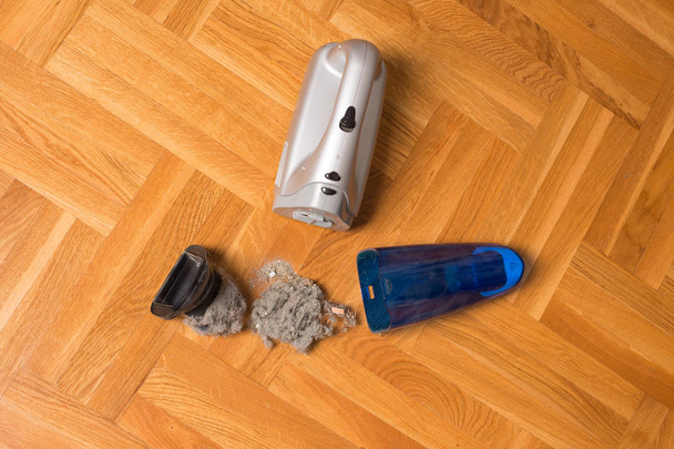 Open handheld vacuum cleaner with filter and dirt on floor - Photo, Image