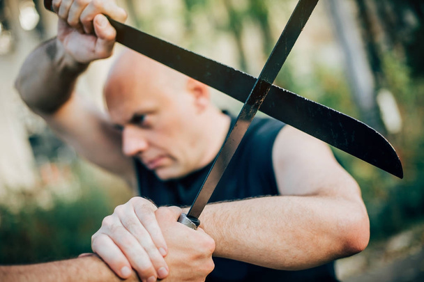 Kampfsportlehrer demonstriert Macheten-Kampf. langes Messer - Foto, Bild