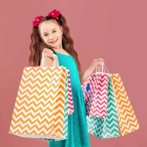 Verkoop. Schattig klein meisje met veel boodschappentassen. Portret van een ki - Foto, afbeelding