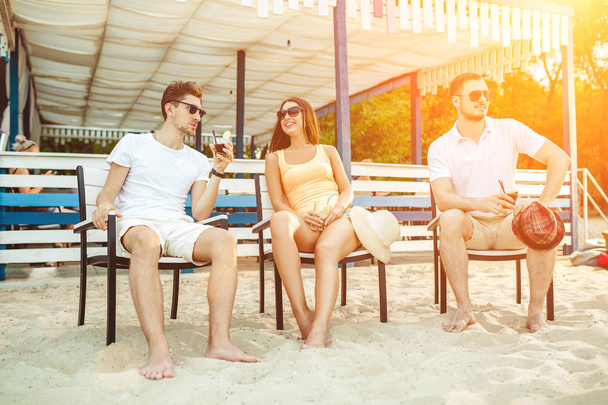 Young people enjoying summer vacation sunbathing drinking at beach bar - Foto, Bild