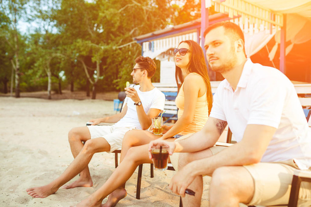 Jovens desfrutam de férias de verão tomando banho de sol bebendo no bar da praia
 - Foto, Imagem