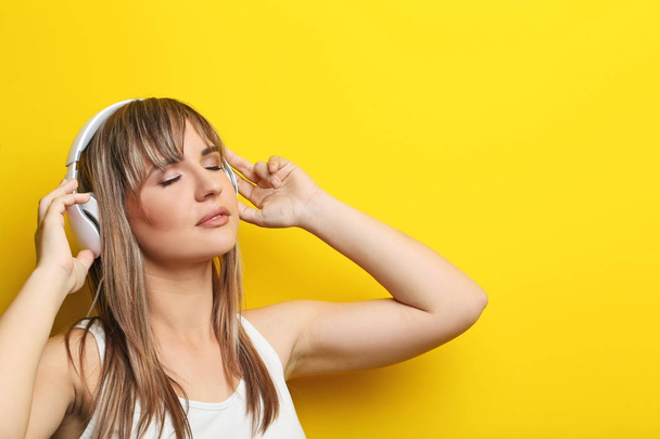 Portrait of young woman with headphones on yellow background - Foto, afbeelding