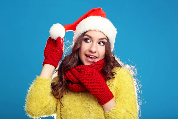 Beautiful young girl in yellow sweater, gloves, scarf and santa  - Foto, Bild