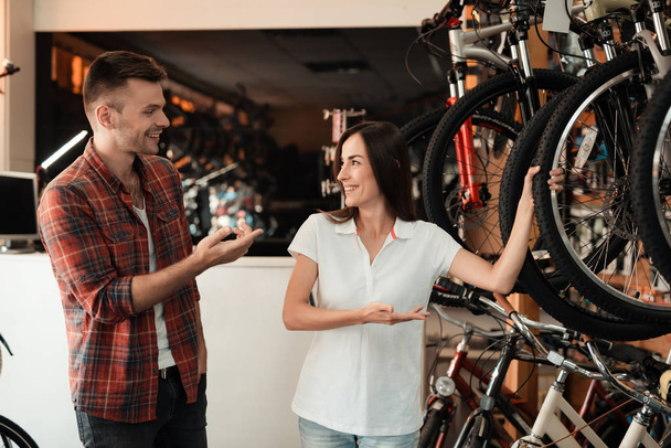 Una chica consultora muestra al comprador en una tienda de bicicletas
. - Foto, imagen
