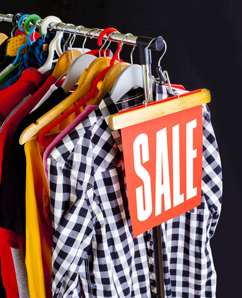 Sale in a clothing store - discount sign at a clothes rack. - 写真・画像