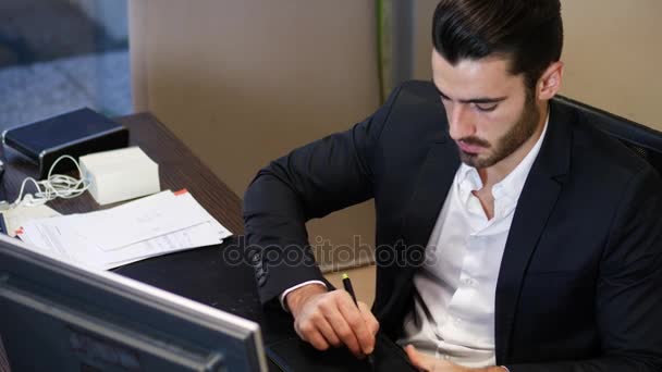 Concentrated man using graphic tablet in office - Video