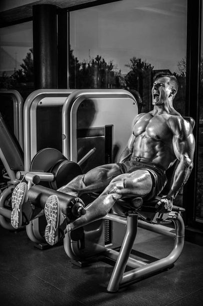 Ejercicios de la pierna - Hombre haciendo pierna con la máquina en el gimnasio
 - Foto, Imagen