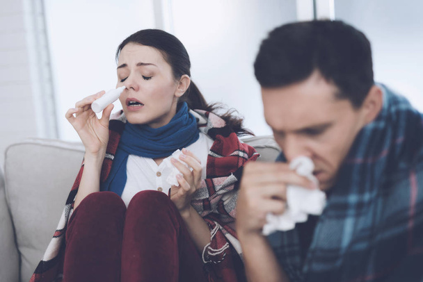 The couple is sitting on the couch wrapped in blankets. Man and woman are sick. They have a bad cold - Foto, Imagen