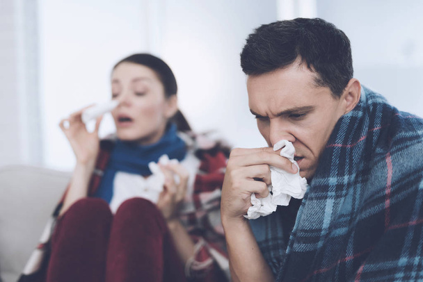 The couple is sitting on the couch wrapped in blankets. Man and woman are sick. They have a bad cold - Foto, Imagen