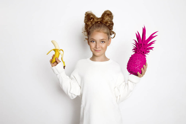 Cute, beautiful blonde young girl with bow from hair. Beauty and joyful girl, she holding colorful fruits. - Photo, Image