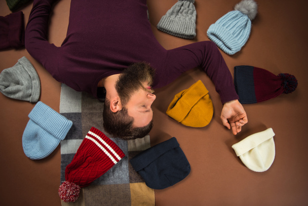 man lying between scattered hats  - Photo, Image