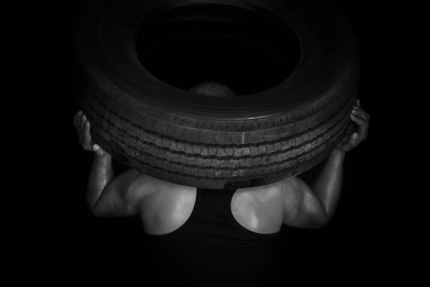 Strong worker holds big truck tire - Photo, Image