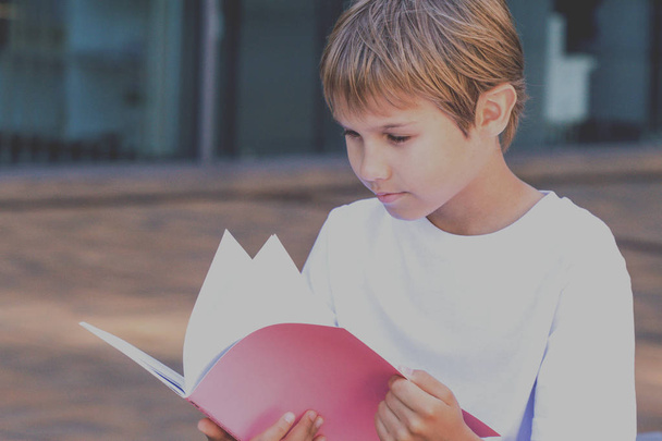 少年は、本を読む。子供の屋外での宿題します。学校コンセプトに戻る. - 写真・画像