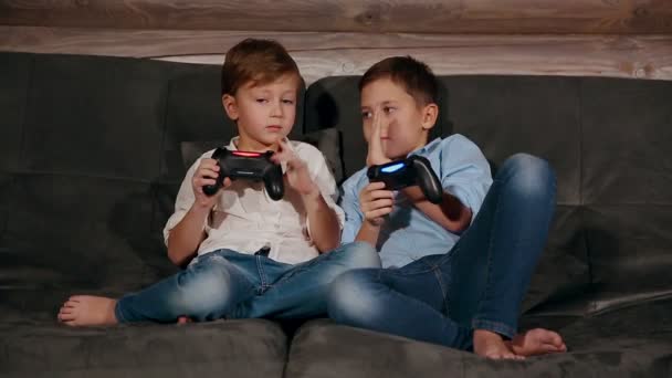 Dois irmãos sentados no sofá e muito emotivos jogando videogames com joystick sem fio
. - Filmagem, Vídeo
