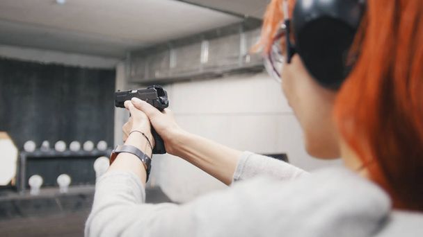 Woman shooting with a gun in shooting gallery - Photo, Image