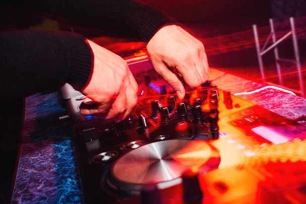 hands of a professional DJ playing and mixing music with bright light effects - Photo, Image