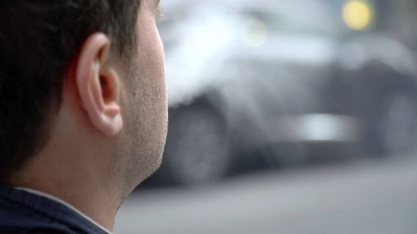 Über-Schulter-Perspektive eines jungen urbanen Millennial-Hipster-Mannes, der draußen auf der Straße E-Cig-Vape raucht. atmen verdampften Rauch aus, der durch aromatisiertes Öl entsteht. - Foto, Bild