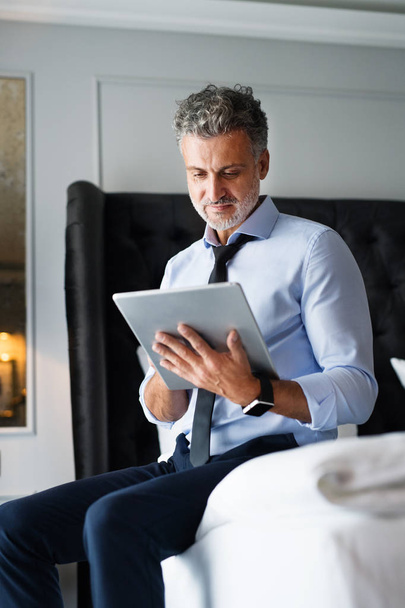 Mature businessman with tablet in a hotel room. - Photo, Image