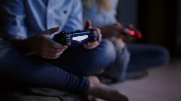 Közeli kép a botkormányt használ egy vezeték nélküli játék a konzol éjjel kezét. A fény, a Tv-készülékből. Két ember. - Felvétel, videó