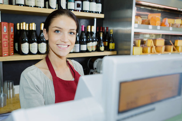 beautiful female food store employee at the cashier smiling - Foto, Bild