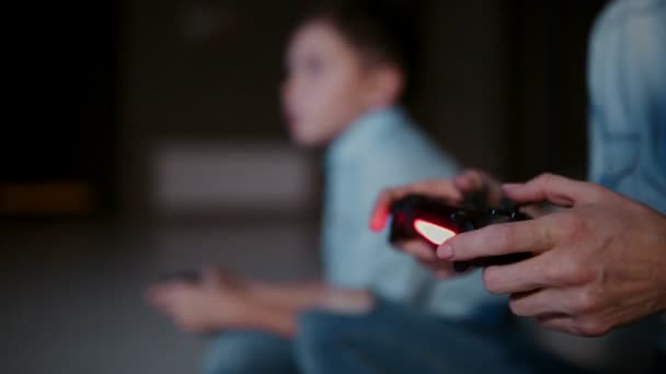 Handen met een controller op een game console, en op de achtergrond de jongen kijkt naar de kraan en het spelen van videospellen. De focus wordt verplaatst van de ene naar de andere. - Video