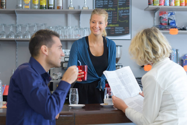 young barista serving coffee to a couple in cafe - Foto, Bild
