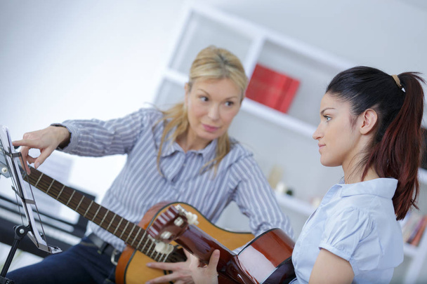 mature female teaching her student how to play guitar - Foto, imagen
