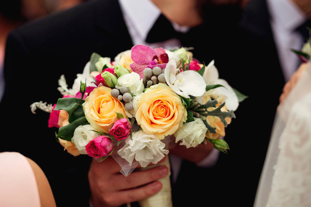 Жених в свадебном костюме держит букет для своего любовника.
 - Фото, изображение