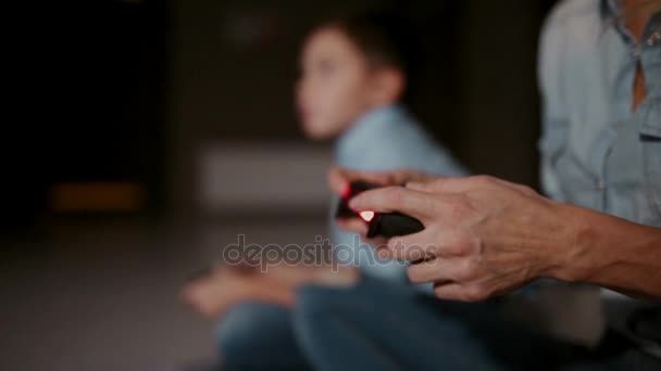 Ręce, trzymając kontroler do konsoli do gier, a w tle chłopiec patrzy na kran i grania w gry wideo. Fokus jest przenoszony z jednego do drugiego. - Materiał filmowy, wideo