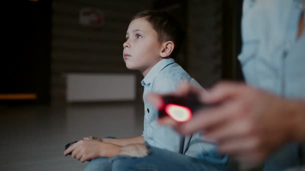 Manos sosteniendo un controlador a una consola de juegos, y en el fondo el niño mira el grifo y juega videojuegos. El enfoque cambia de uno a otro
. - Metraje, vídeo