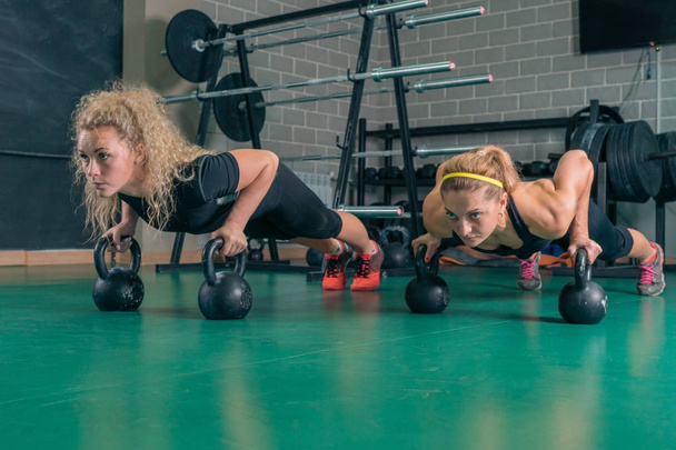 Fitness girls do push-ups with weights in the gym - Foto, afbeelding