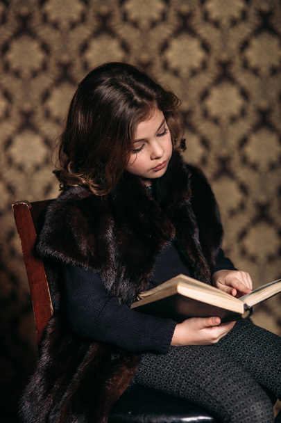 Belle petite fille lit un livre dans la bibliothèque
. - Photo, image