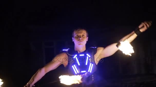 Fire show performance. Handsome male fire performer twirling and tossing up fire baton staff ignited from both sides. - Footage, Video